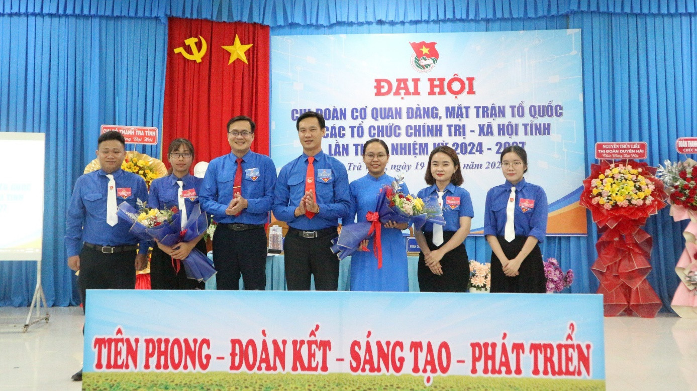 A group of people standing in front of a banner

Description automatically generated