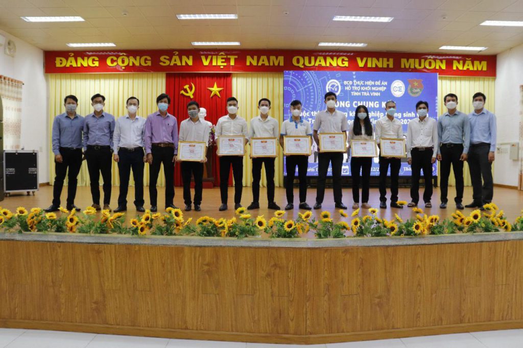 A group of people standing in front of a sign Description automatically generated with low confidence