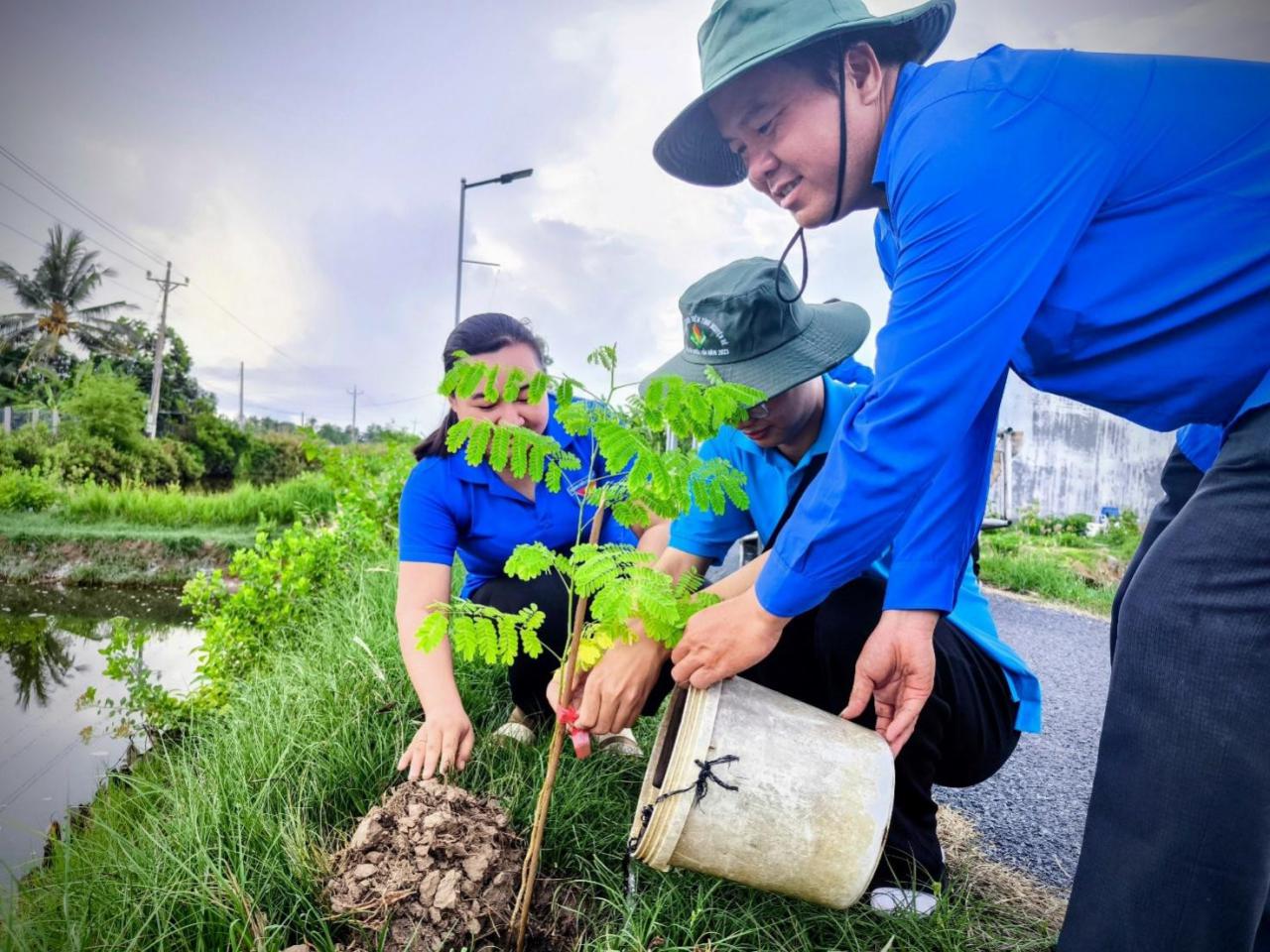 A group of people planting a tree Description automatically generated