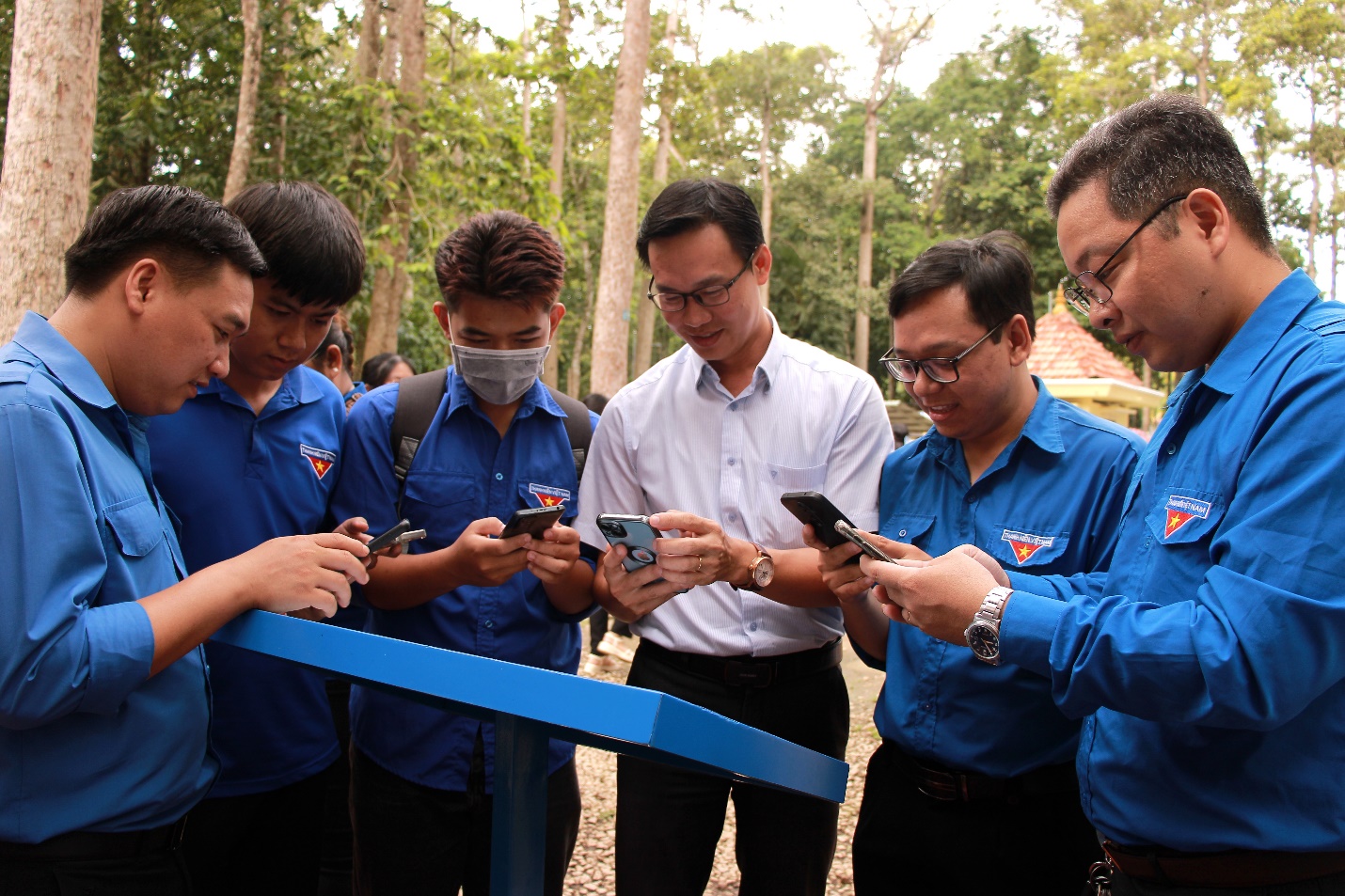 A group of men looking at their phones Description automatically generated