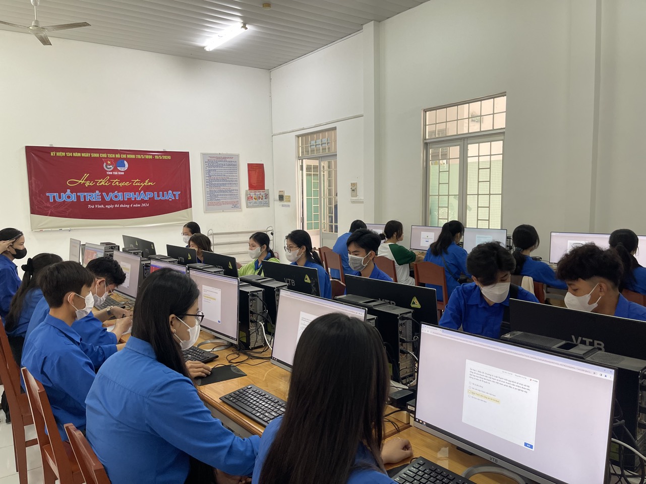 A group of people in a room with computers

Description automatically generated