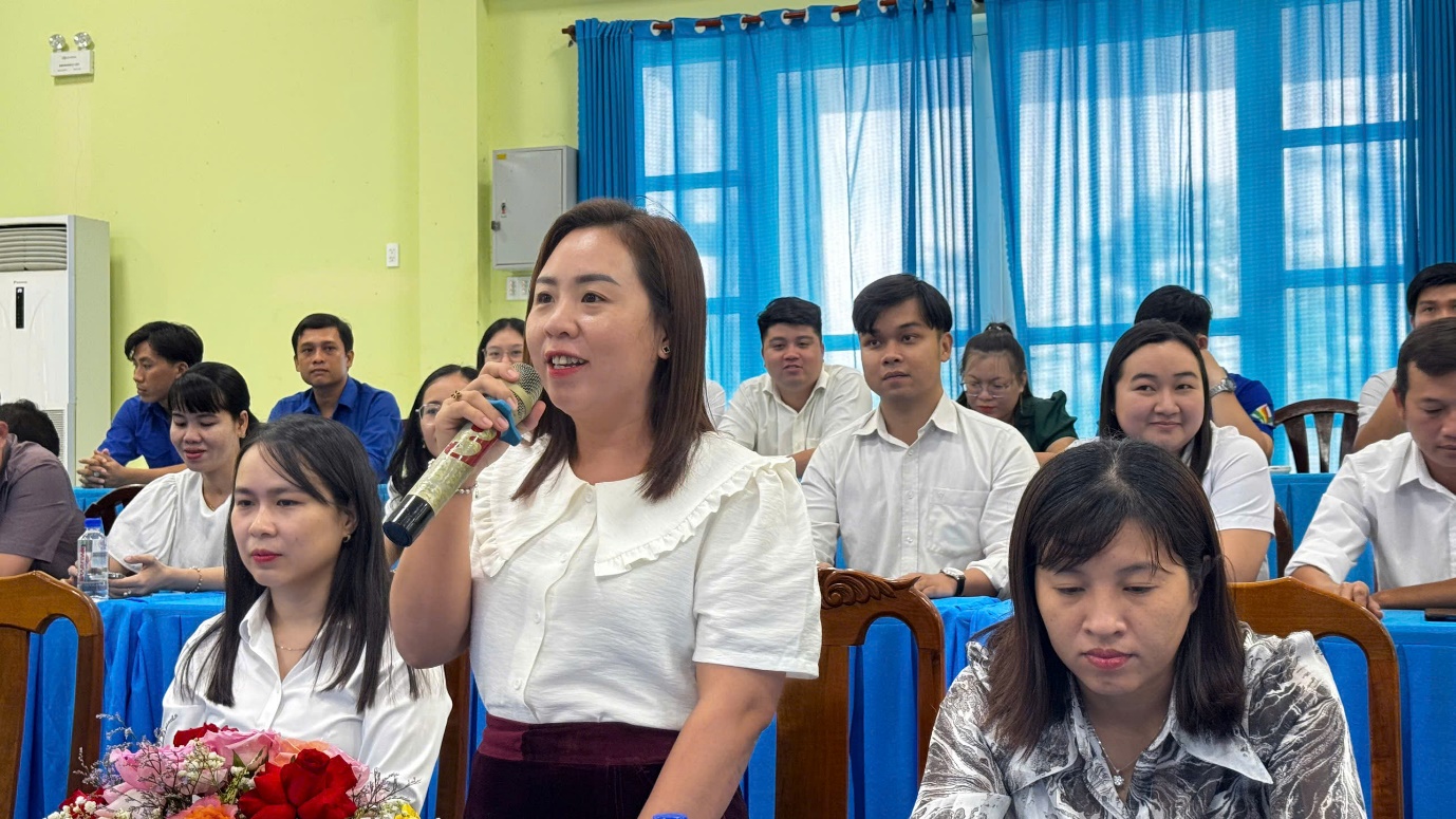 A person holding a microphone in front of a group of people

Description automatically generated